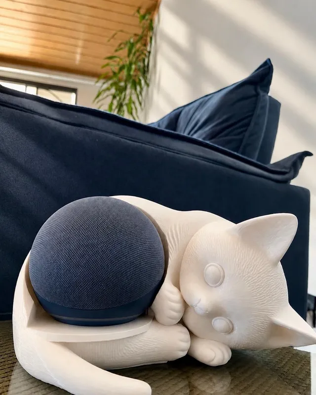 Gato branco dormindo abraçado a uma caixa de som esférica azul